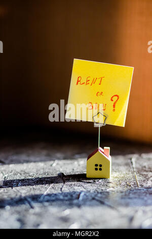 Modèle de maison comme symbole sur fond de soleil. Le texte écrit à la main : Acheter ou louer ? Banque D'Images