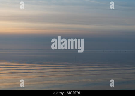 Le lac Trasimeno (Ombrie) au crépuscule, avec des tons doux dans le ciel et l'eau, beaux reflets d'or sur l'eau et d'un lointain bird flying Banque D'Images