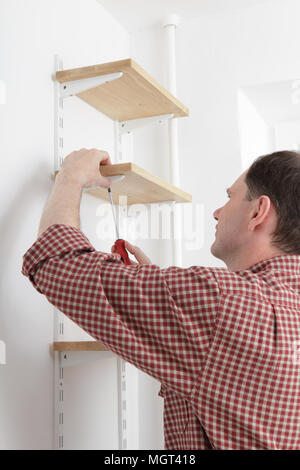 L'homme l'installation d'étagères en bois sur les supports Banque D'Images