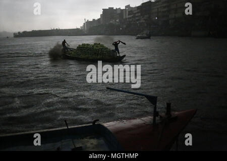 Dhaka, Bangladesh. Apr 28, 2018. Une filature du travail towel on head et un marin bateau de germination pour sauver de la pluie comme ils livrent watermelon dans la rivière Buriganga. Credit : Md. Mehedi Hasan/ZUMA/Alamy Fil Live News Banque D'Images