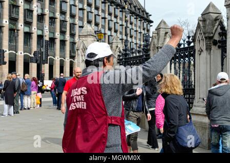 Homme asiatique d'âge moyen dans la rue devant les Chambres du Parlement Westminster prêcher sur les avantages de Jésus aux passants London England UK Banque D'Images