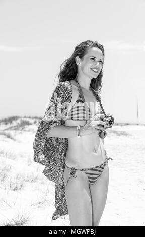 Ambiance bohème. vacances boho smiling young woman in bikini sur la plage avec vintage film appareil à distance dans la Banque D'Images