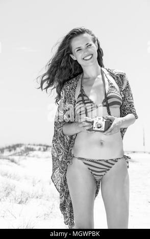 Ambiance bohème locations. Hipster Portrait of happy young woman in bikini sur la plage avec appareil photo rétro Banque D'Images