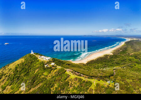 Phare blanc donnant sur des eaux cristallines de l'océan Pacifique et la plage de sable du haut de smoky cape pointe dans Arakoon parc national. Banque D'Images