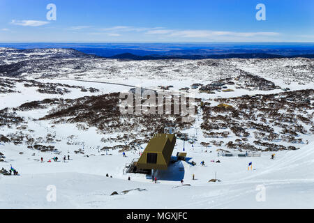 Retour en haut de la montagne dans les montagnes enneigées perisher en regardant ski resort et le télésiège de l'infrastructure avec des skieurs et planchistes au-dessus Banque D'Images