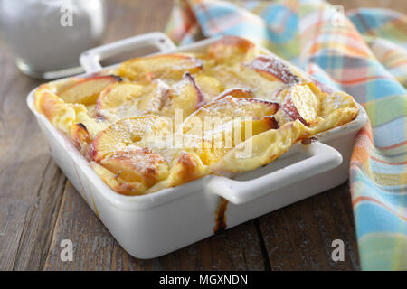 Clafoutis aux pêches dans un plat allant au four, sur une table rustique Banque D'Images