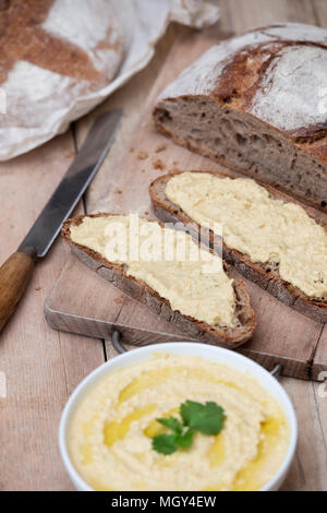 Pain au levain et pain au levain d'épeautre avec du hoummos sur une carte de pain. UK. UK Banque D'Images