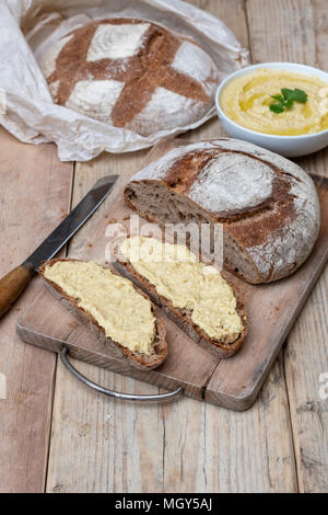 Pain au levain et pain au levain d'épeautre avec du hoummos sur une carte de pain. UK Banque D'Images