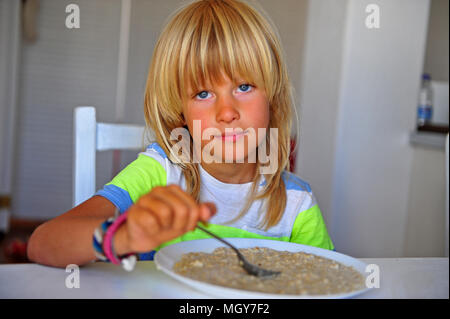 De longs cheveux blonds boy eating flocons d'avoine dans la cuisine Banque D'Images