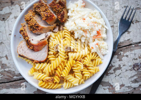 Les longes de porc à la moutarde avec du chou et fusillis et salade de carottes Banque D'Images