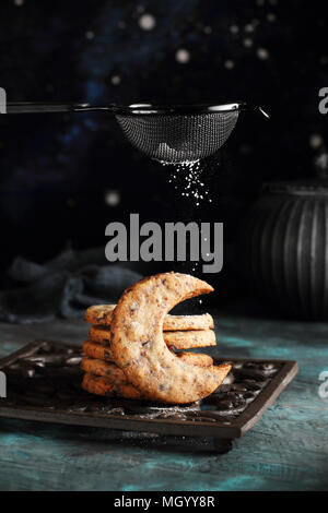 Les cookies dans la forme d'un croissant avec des morceaux de chocolat sont saupoudrées de sucre en poudre Banque D'Images