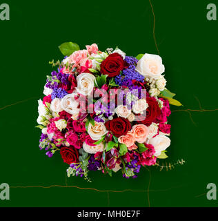 Vue de dessus d'un beau bouquet de fleurs, roses multicolores avec des feuilles vertes, sur un carré de marbre vert avec nervures d'orange Banque D'Images