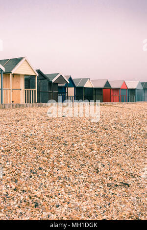 Cabines de plage aux tons colorés répartis le long de Calshot Spit sur un jour nuageux, couvert, Calshot England, UK Banque D'Images