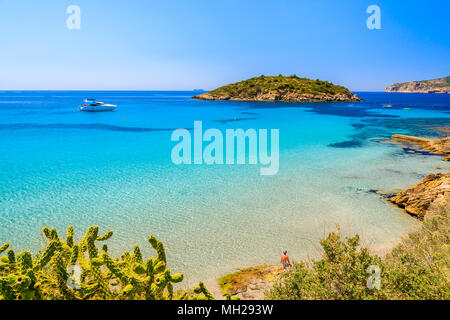 Un homme assis sur un rocher et regarder la mer, belle plage et village de Sant Elm, l'île de Majorque, Espagne Banque D'Images