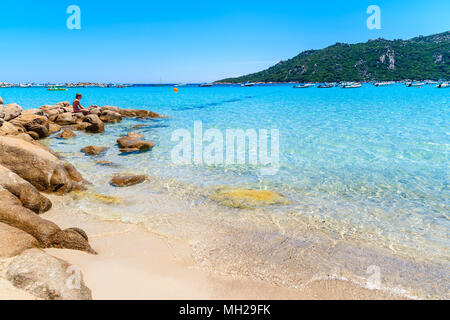 Plage de Santa Giulia, l'île de Corse - JUN 22, 2015 : Jeune femme assise sur des rochers sur une plage magnifique avec de l'eau claire comme du cristal. Cette île française est pop Banque D'Images