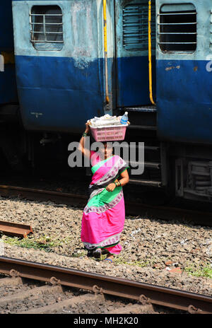 Une femme transportant les marchandises sur la tête qu'elle a été la vente aux passagers de ce train indien arrêté Banque D'Images