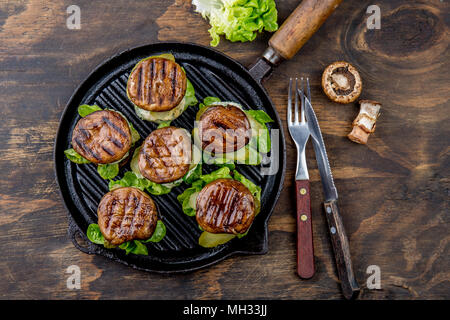 Pain hamburger aux champignons portobello grillés sur le poêle en fonte ob fond de bois, vue du dessus. Banque D'Images