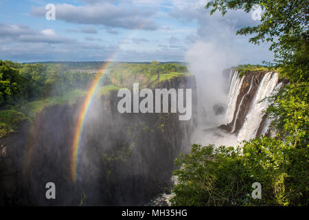 Les eaux tumultueuses de Victoria Falls le brouillard de pulvérisation dans l'air, créant un arc-en-ciel, la brume contribue également à l'épaisseur, la végétation luxuriante Banque D'Images