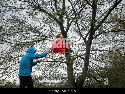 Homme avec un parapluie rouge le jour du vent/de l'orage. ROYAUME-UNI Banque D'Images
