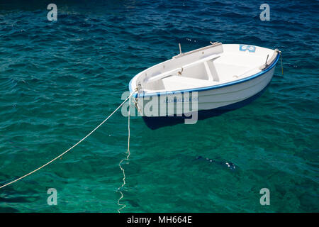 Petit bateau de pêche grec flottant dans l'eau turquoise Banque D'Images