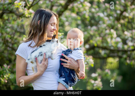 Maman heureuse, tenant son cute baby boy in spring park, arbres en fleurs Banque D'Images