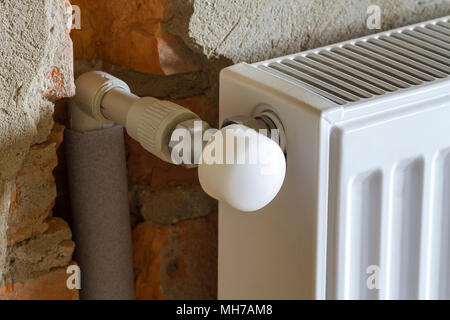 Close-up Vue de côté du radiateur de chauffage installé isolé sur la paroi rugueuse brique dans une salle vide d'un appartement nouvellement construit ou maison. Construc Banque D'Images