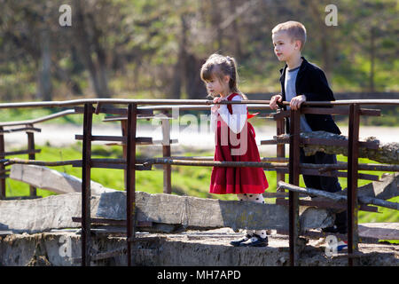 Deux jolies blondes enfants, petite fille aux cheveux long et cute boy leaning on garde-corps en bois de vieux pont à attentivement sur chaude journée ensoleillée. Enfant Banque D'Images