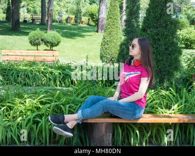 Beautiful Girl sitting on bench dans Green Park, journée ensoleillée. La jeune fille d'apparence Asiatique Banque D'Images