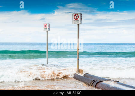 Les panneaux d'avertissement et d'un tuyau sur une plage à Sydney en Australie. Banque D'Images