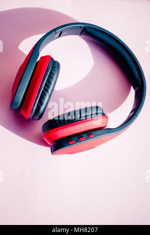 Casque sans fil noir rouge isolé sur fond rose et région de la publicité que la technologie numérique .bluetooth et le clipping path.L'écoute de la musique un concept. Banque D'Images
