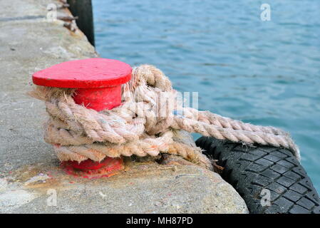 Stand rouge sur le quai avec une corde et tire Banque D'Images