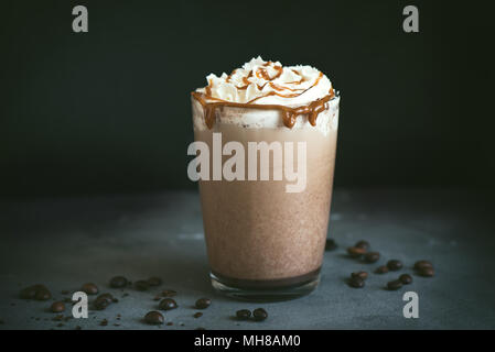 Frappe à froid (Café frappuccino) avec de la crème fouettée et caramel sur fond sombre, copiez l'espace. Banque D'Images