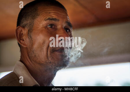 Yangshuo, Chine - le 2 août 2012 : Portrait of a Chinese man smoking a cigarette dans un bateau dans le fleuve Li, près de la ville de Yangshuo, en Chine. Banque D'Images