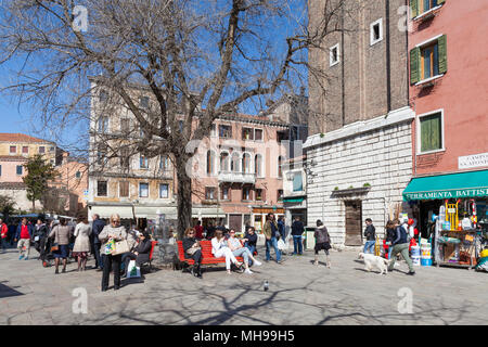 Les Vénitiens locales profitant du soleil du printemps, Campo Santi Apostoli Cannaregio, Venise, Italie assis sur des bancs, les boutiques et un chien Banque D'Images