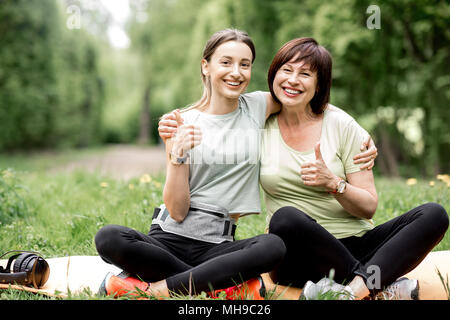 Les jeunes et l'aîné woman doing yoga dans le parc Banque D'Images