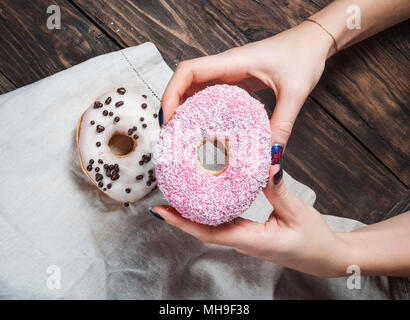 Cueillette à la main des femmes sweet donut sucré à partir de la table de cuisine en bois rustique, de savoureux beignets boulangerie passage tourné, vue du dessus Banque D'Images