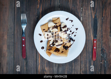 Des crêpes au chocolat et banane sur un fond de bois. Banque D'Images