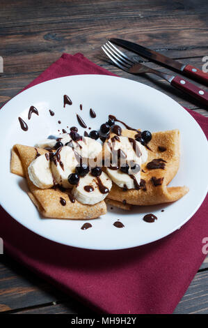 Des crêpes au chocolat et banane sur un fond de bois. Banque D'Images