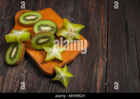 Fruits tropicaux frais tranchés sur bois y compris kiwi et carambole. Banque D'Images