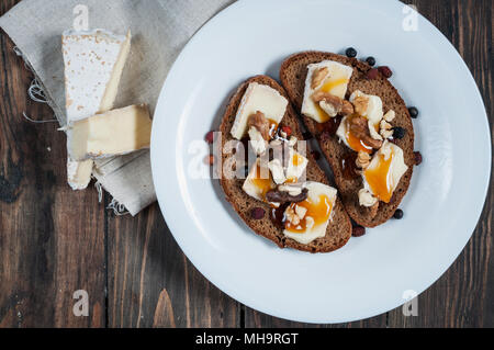 Brie fondu au miel, noix de pin et les noix sur du pain noir. Banque D'Images
