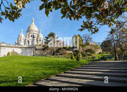 La basilique du Sacré-Cœur de Paris, en haut de la colline de Montmartre vue depuis le parc Louise Michel avec le feuillage et les escaliers à l'avant-plan Banque D'Images