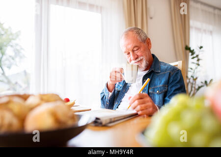 Man eating breakfast et faire les mots croisés à la maison. Banque D'Images