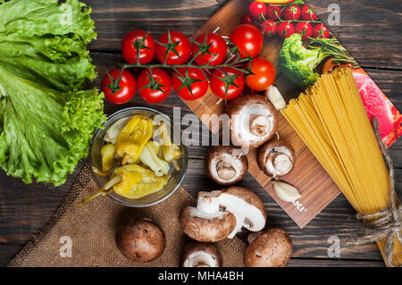 Les pâtes, tomates, salade, poivrons, champignons et livre de recettes sur fond de table en bois. Banque D'Images