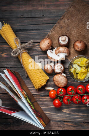 Les pâtes, tomates, salade, poivrons, champignons et livre de recettes sur fond de table en bois. Banque D'Images