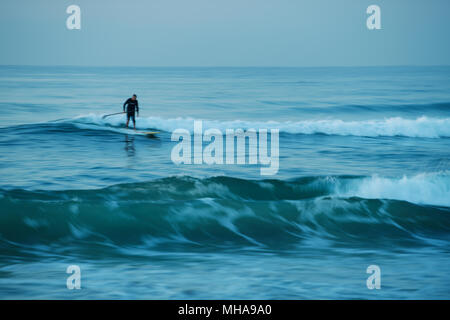 Durban, le KwaZulu-Natal, Afrique du Sud, flou de mouvement, homme adulte surf une vague sur stand up paddle board, plage d'Umhlanga Rocks Banque D'Images