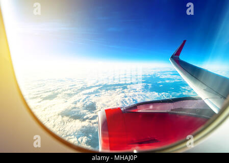 Voler avec un avion, voir des ailes, du moteur, le ciel et les nuages à travers la fenêtre de l'avion en vol sur une belle journée ensoleillée Banque D'Images