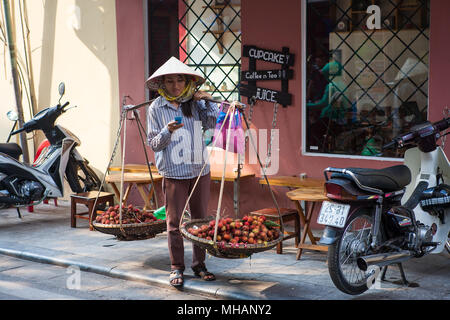 Vendeur de rue traditionnels avec des paniers de chape, leaf-hat et téléphone mobile, Mã Mây, Hoàn Kiếm, Hà Nội, Vietnam Banque D'Images