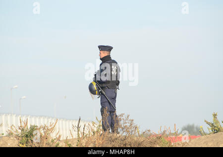 Un agent de police français monte la garde au cours de l'évacuation de la jungle de Calais. La Jungle était un camp de migrants dans le nord de la ville française de Calais. Le camp attiré des migrants et des réfugiés du Moyen Orient, Afrique du Nord et l'Afrique subsaharienne qui ont planifié d'entrer illégalement au Royaume-Uni. Finalement, les autorités françaises ont été obligés de fermer la Jungle parce qu'il était devenu hors de contrôle et devient à la fois un risque pour la santé publique et un centre d'activité criminelle. La Jungle de Calais a été fermé en octobre 2016. Banque D'Images