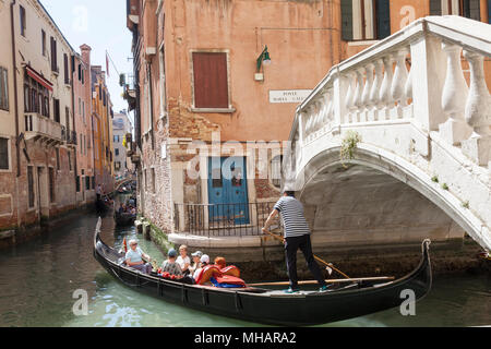 Gondolier suivi d'un étroit canal occupé retour en télécabine avec ses touristes, Rio de la Vesta, San Marco, Venise, Vénétie, Italie tournant comme il passe Pon Banque D'Images