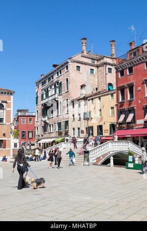 Bâtiments colorés et pont sur le Campo dei Frari, San Polo, Venise, Vénétie, Italie avec une femme locale promener son chien et les touristes Banque D'Images